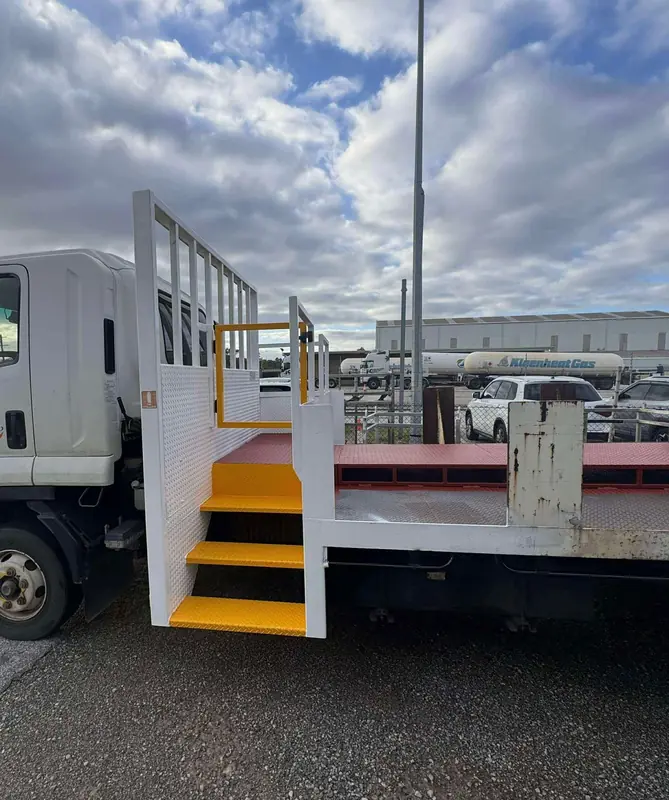 Truck-mounted steel access stairs with yellow safety handrails fabricated by Oxford Engineering